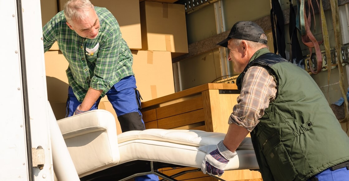 Movers placing furniture inside a moving van.