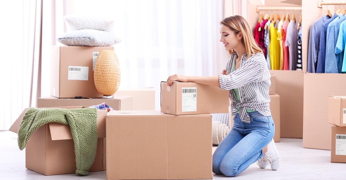 Young woman packing wardrobe boxes on moving day