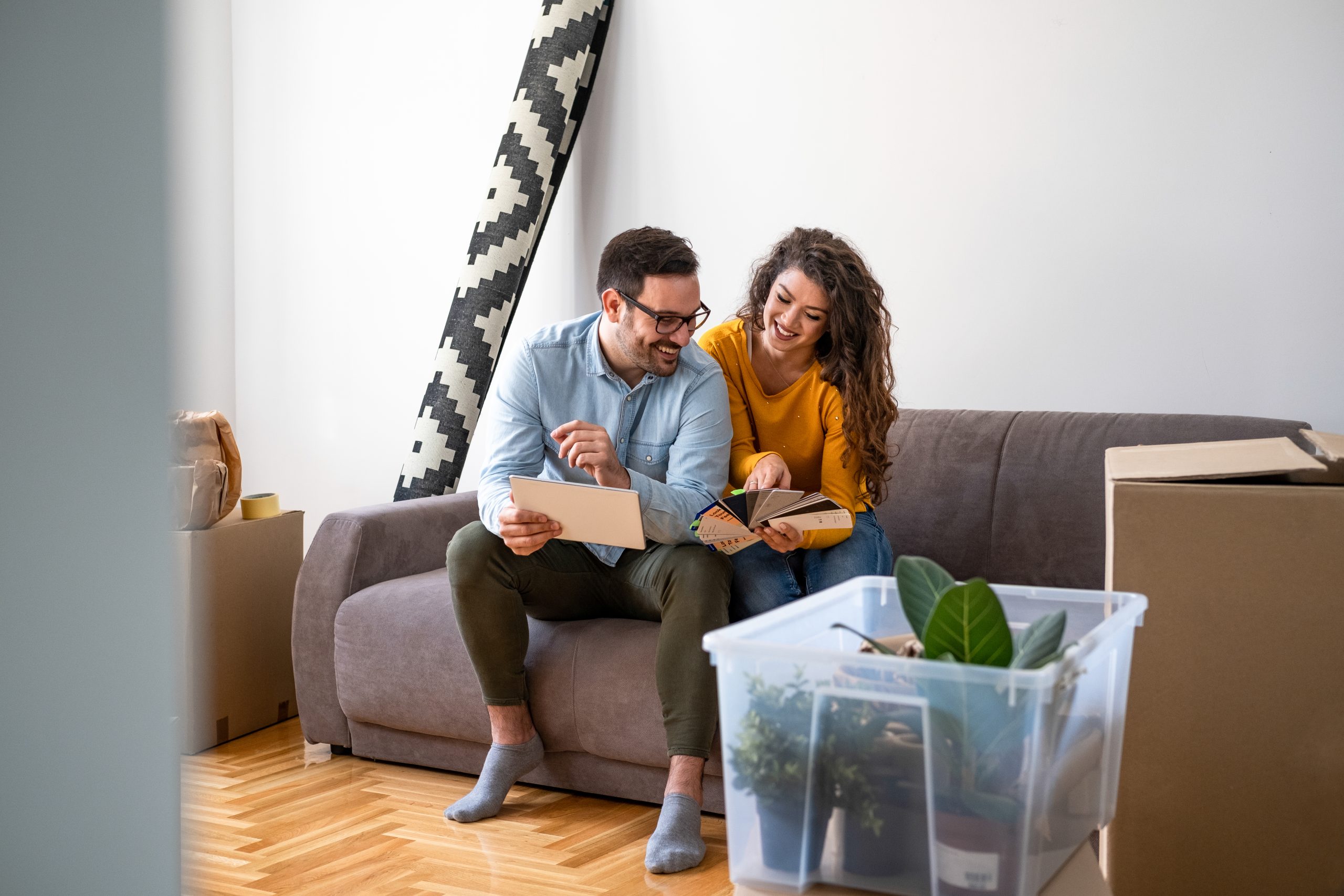 Smiling,Couple,Sitting,On,The,Sofa,,Choosing,Paint,Colors,From