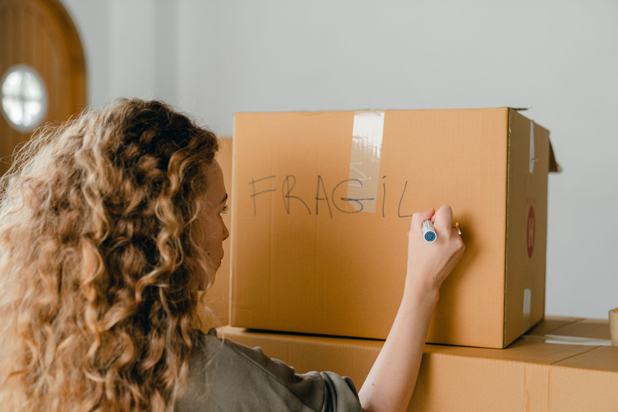 Woman writing fragile on a moving box.
